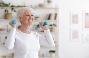 Smiling senior lady exercising with dumbbells to live a healthy, active lifestyle