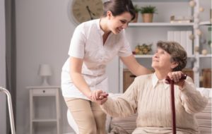 Elderly woman smiling up at a caregiver while receiving assisted care