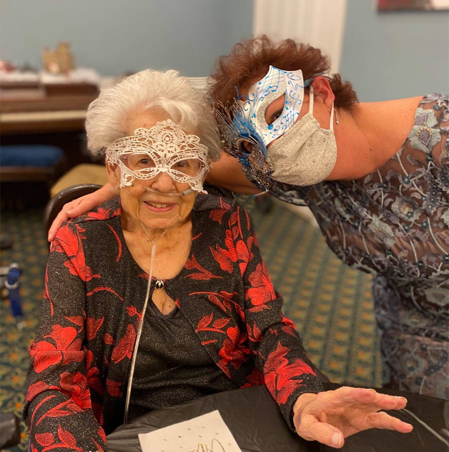 Two elderly women wearing fancy masks at our masquerade party.