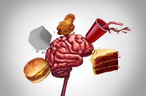 An illustration of a human brain surrounded by junk food showing foods that are bad for the brain and memory.