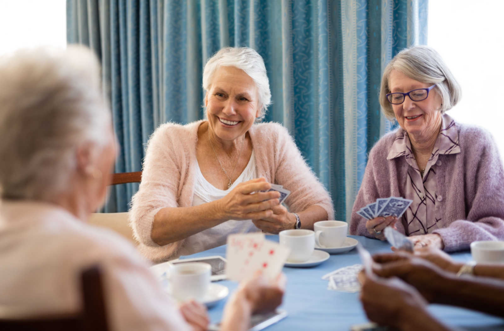 A group of senior living residents enjoying social connection while playing a card game.