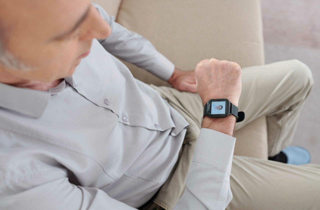A senior man sitting on a couch and watching a video on his smart watch.