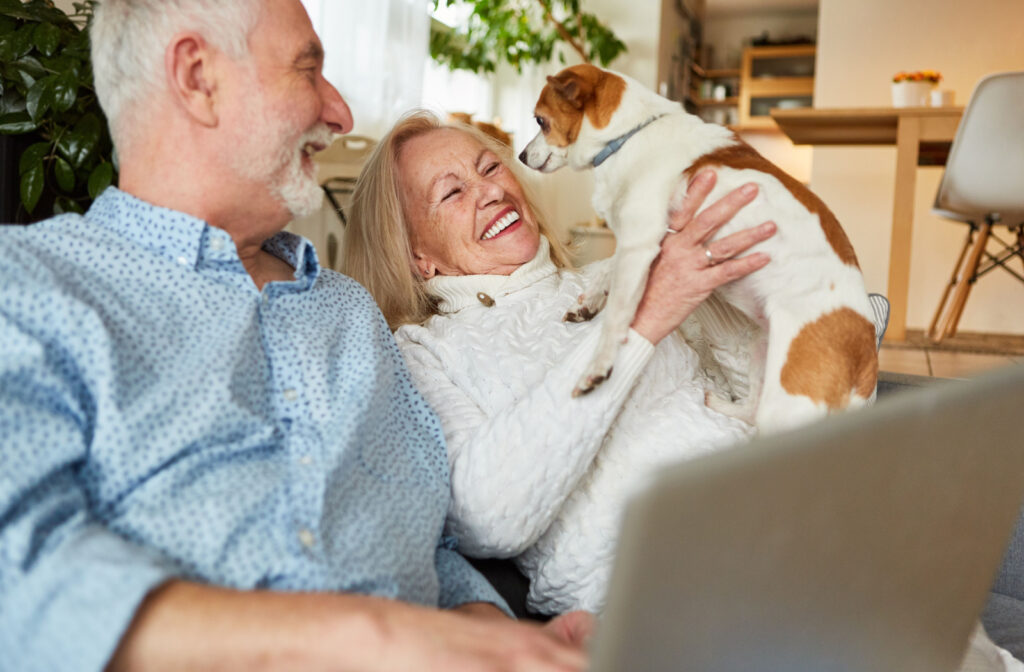 A senior man and a senior woman playing with a small dog in a living room