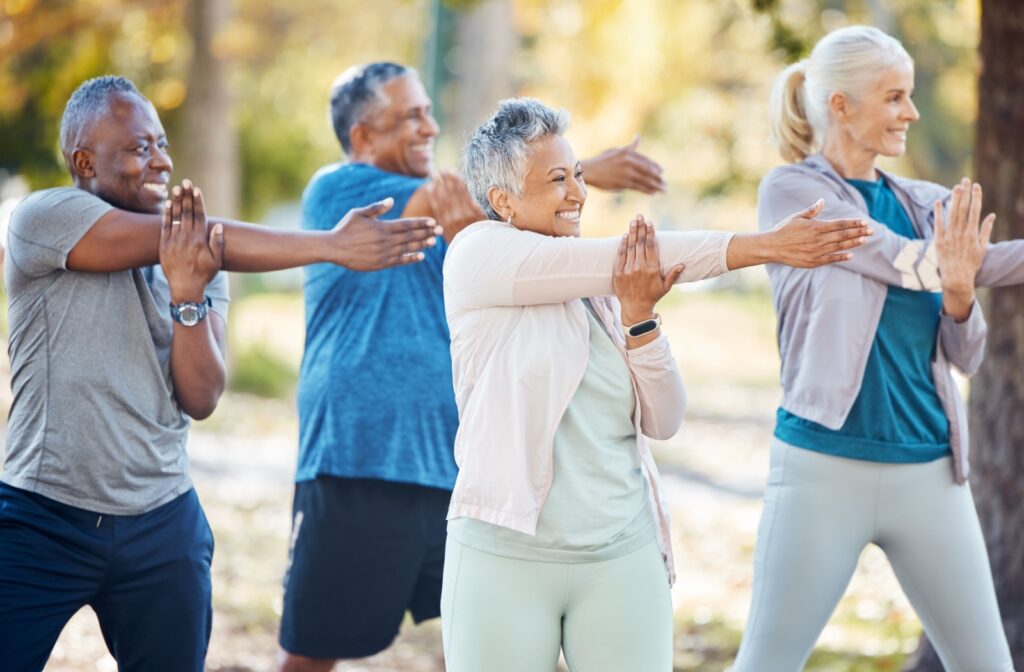 a group of seniors performing stretching exercises in a park.