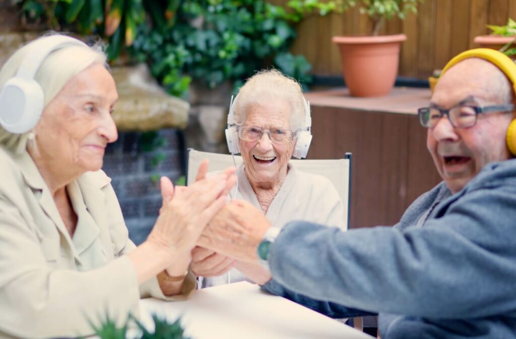 A group of seniors laugh, smile, and clap along to music during a music therapy class in a memory care community.