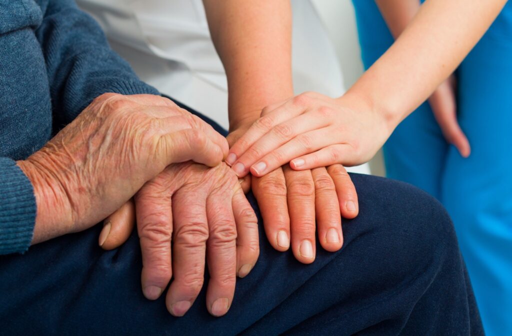 A young adult touches the hand of their older loved one to show them support about their recent memory problems