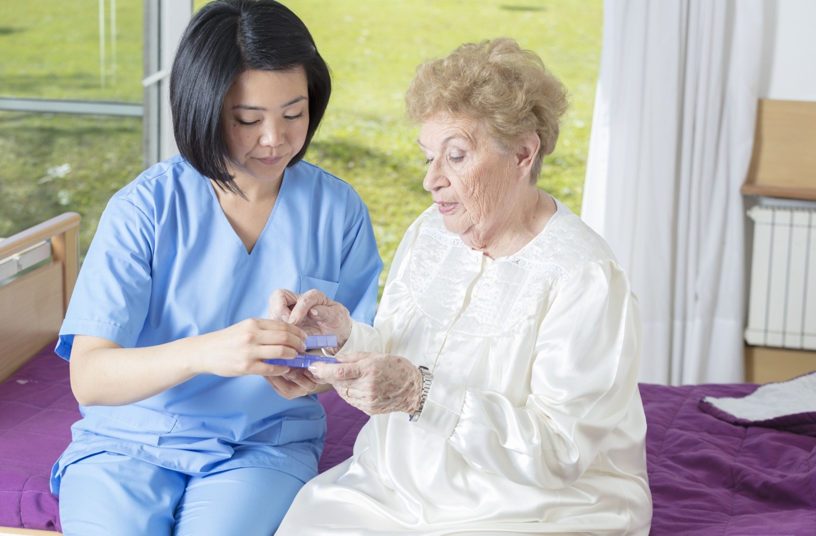 A caregiver helps a senior with their medication for the day.
